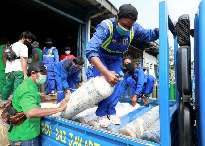 Des employés portent des bouteilles d’oxygène dans une usine à Jakarta, en Indonésie, le 6 juillet 2021.
