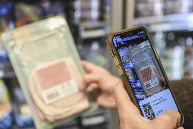 Un client utilisant l’application Yuka, notant la qualité nutritionnelle des produits industriels, dans un supermarché à Paris, en 25 novembre 2020.