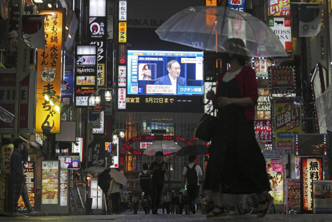 Des Japonais dans les rues de Tokyo, où est retransmise l’allocution du premier ministre, Yoshihide Suga, le 8 juillet 2021.