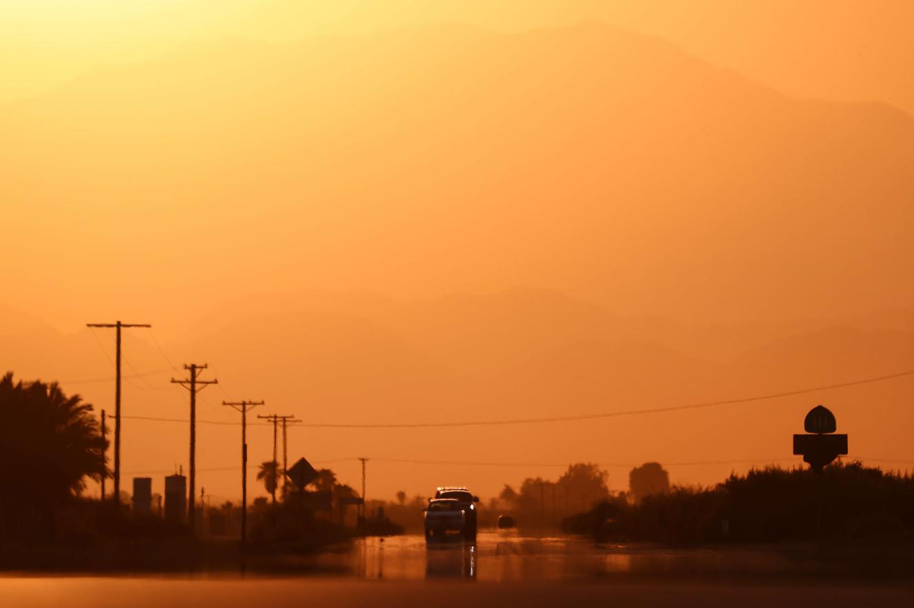 Cars seen through a mirage caused by high air temperatures, Thermal, California, July 10, 2021.