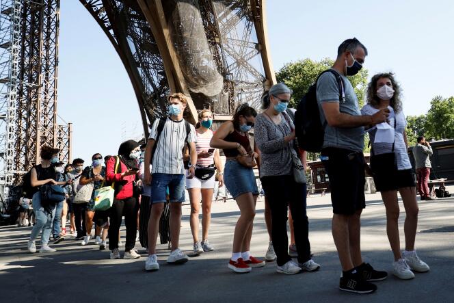 Le 25 juin 2020, des visiteurs portant des masques font la queue en attendant la réouverture partielle de la tour Eiffel, à Paris.