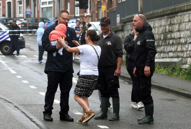 Een vrouw wordt herenigd met haar kind nadat reddingsteams haar overstroomde huis in Hognoul, aan de rand van Luik, op 15 juli 2021 hebben ontruimd.