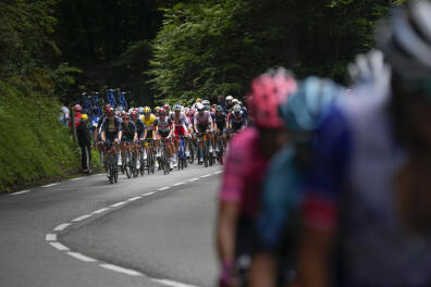 Team Ineos Grenadiers set the pace of the pack as they chase after the breakaway group, right, during the eighteenth stage of the Tour de France cycling race over 129.7 kilometers (80.6 miles) with start in Pau and finish in Luz Ardiden, France,Thursday, July 15, 2021. (AP Photo/Christophe Ena)