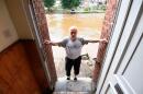A local resident stands in his house facing the destroyed and flooded road in Trooz, near Liege, on July 16, 2021. The death toll from devastating floods in Europe soared to at least 126 on July 16, 2021, most in western Germany where emergency responders were frantically searching for missing people. In Belgium, the government confirmed the death toll had jumped to 20 - earlier reports had said 23 dead - with more than 21,000 people left without electricity in one region. / AFP / JOHN THYS 