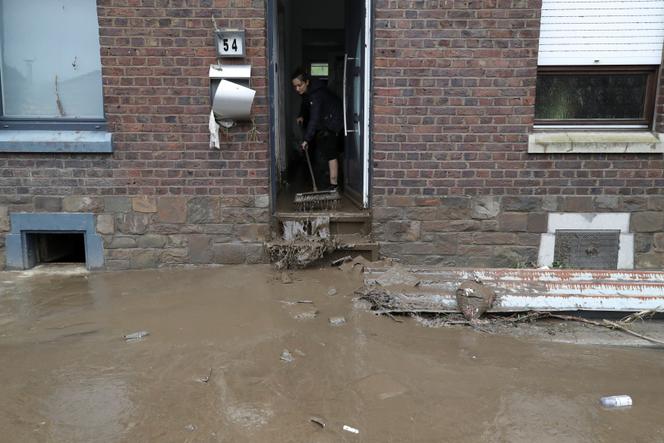 Een vrouw veegt water uit haar ondergelopen huis, na zware regenval, in Trooz, België, 16 juli 2021.