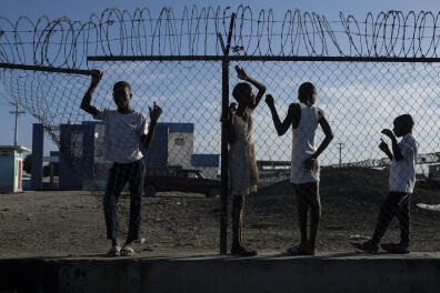 Youths stand at a gate along the seashore in the La Saline neighborhood of Port-au-Prince, Haiti, Monday, July 19, 2021. The country of more than 11 million people are still reeling from the July 7 killing of President Jovenel Moise. (AP Photo/Matias Delacroix)