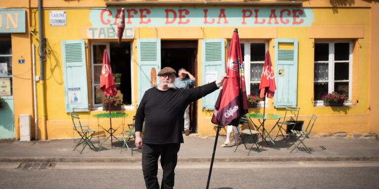 Fabrice Quinart, posant avec un parasol, devant son Café de la Place (Brieulles-sur-Bar, France), le 9 juin 2021.
