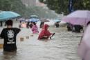 TOPSHOT - This photo taken on July 20, 2021 shows people wading through flood waters along a street following heavy rains in Zhengzhou in China's central Henan province. - China OUT (Photo by AFP) 