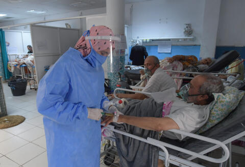 A Tunisian medic provides first aid to COVID-19 patients at the Charles Nicole hospital's emergency room in the capital Tunis, on July 16, 2021. - Overwhelmed by the explosion of COVID-19 cases Tunisia now relies on international aid to deal with the health crisis, a critical situation for the country which had successfully anticipated the first wave of the pandemic. (Photo by FETHI BELAID / AFP)