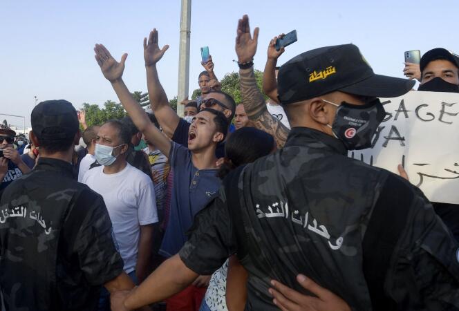 Des agents de sécurité tunisiens retiennent des partisans du président Kaïs Saïed alors qu’ils scandent des slogans dénonçant le principal parti islamiste du pays, Annahda, devant le Parlement qui a été bouclé par l’armée à Tunis, le 26 juillet 2021.