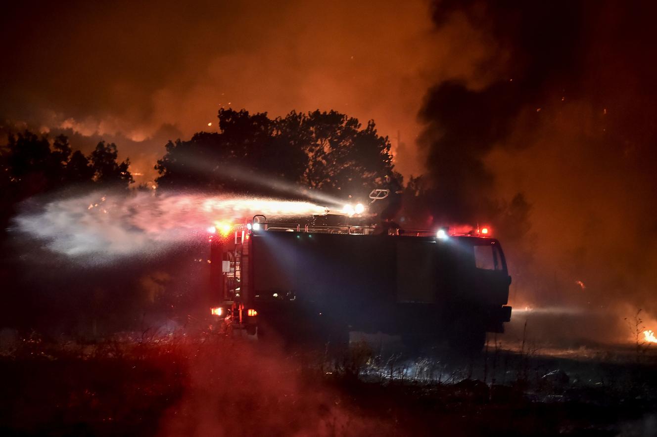 Brandweerlieden bestrijden de vlammen in de buurt van Avidenes, ten noorden van de Griekse hoofdstad, op 5 augustus.