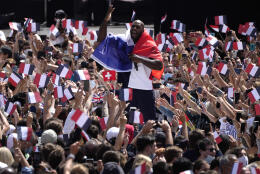 French Olympic heavyweight bronze medallist and mixed team gold medallist in Judoka, Teddy Riner, center, is wrapped in a French flag as he cheers on fans in the Olympics fan zone at Trocadero Gardens in front of the Eiffel Tower in Paris, Sunday, Aug. 8, 2021. A giant flag will be unfurled on the Eiffel Tower in Paris Sunday as part of the handover ceremony of Tokyo 2020 to Paris 2024, as Paris will be the next Summer Games host in 2024. The passing of the hosting baton will be split between the Olympic Stadium in Tokyo and a public party and concert in Paris. (AP Photo/Francois Mori)