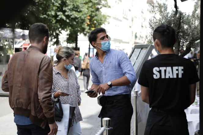 Un serveur contrôle le passe sanitaire de clients d’un restaurant, à Paris, le 9 août 2021.