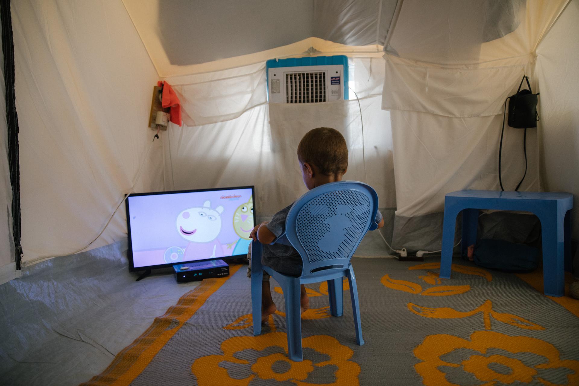 Dans une tente de la section Roj-2, un garçon regarde un dessin animé, le 10 août 2021.
