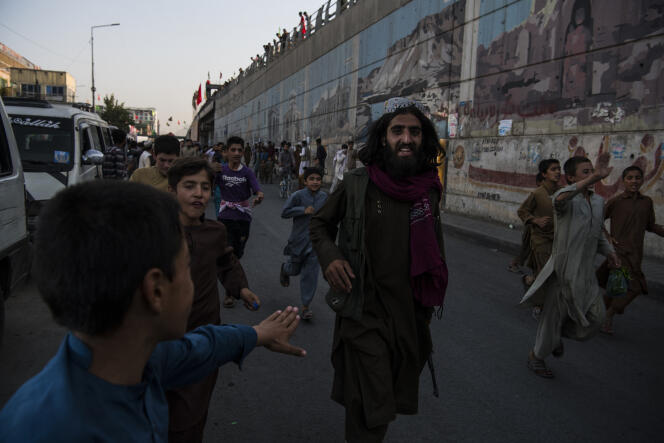 Un combattant taliban, escorté par la foule dans une rue de Kaboul, le 15 août 2021.