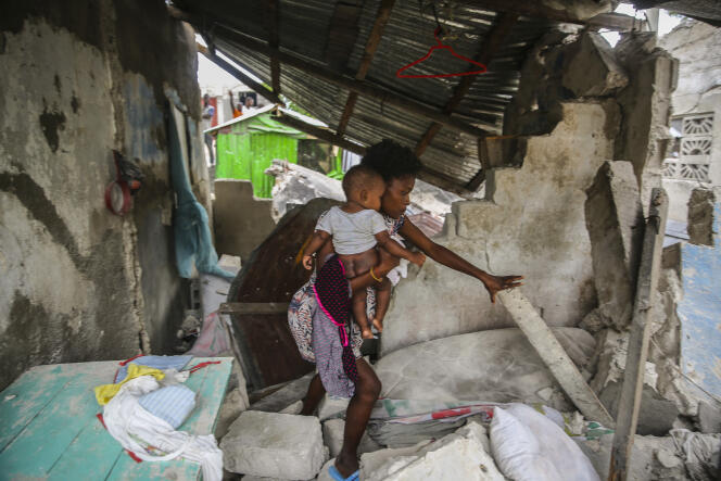 Sunday, August 15, 2021, a woman carries her child as she walks through the remains of her house destroyed by the magnitude 7.2 earthquake that struck Saturday in Les Cayes, Haiti.