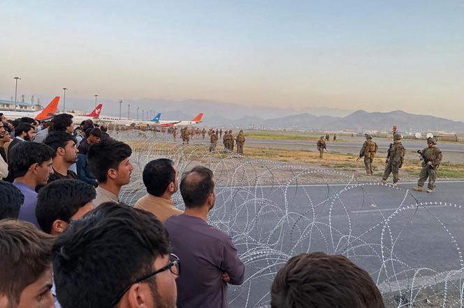 Afghans face American soldiers at Kabul airport on August 16, 2021.
