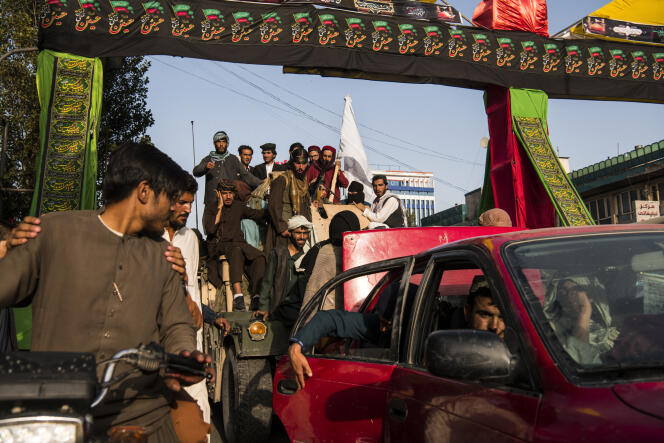 Des combattants talibans, montés sur un 4x4 blindé de fabrication américaine, traversent les rues de l’ouest de Kaboul sous les acclamations des habitants et des passants, le 15 août 2021.