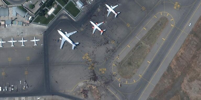 This handout satellite image released by Maxar Technologies shows a crowds of people on the tarmac, during the chaotic scene underway at Kabul’s Hamid Karzai International Airport in Afghanistan as thousands of people converged on the tarmac and airport runways as countries attempt to evacuate personnel from the city on August 16, 2021. US soldiers killed two armed men at Kabul's airport on August 16, 2021 as thousands of people flocked to the terminal seeking to flee Afghanistan, a Pentagon official said. - RESTRICTED TO EDITORIAL USE - MANDATORY CREDIT 