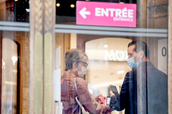 A woman presents her health pass to a security guard at the entrance of department stores in Paris in August 2021.