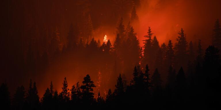 TOPSHOT - In this long exposure image taken at night, plumes of wildfire smoke rise as trees burn during the Dixie Fire on August 18, 2021 near Susanville, California. The wildfire in Northern California continues to grow, burning over 626,000 acres according to CalFire. (Photo by Patrick T. FALLON / AFP)
