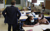 French President Emmanuel Macron speaks with children during a visit at Bouge primary school in Malpasse district of Marseille, southern France, Thursday Sept. 2, 2021 as twelve million children in France went back to school Thursday for the new academic year, wearing face masks as part of rules aimed at slowing down the spreading of the virus in the country. French President Emmanuel Macron, accompanied by several ministers, is on a three-day visit to the southern city of Marseille to address security, education and housing issues. (AP Photo/Daniel Cole, pool)