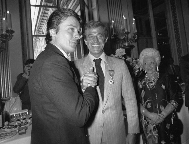 Alain Delon et Jean-Paul Belmondo (avec en arrière-plan, Madeleine Belmondo, la mère de l’acteur) lors d’une cérémonie pour la Légion d’honneur, en septembre 1980,  à l’Elysée à Paris.