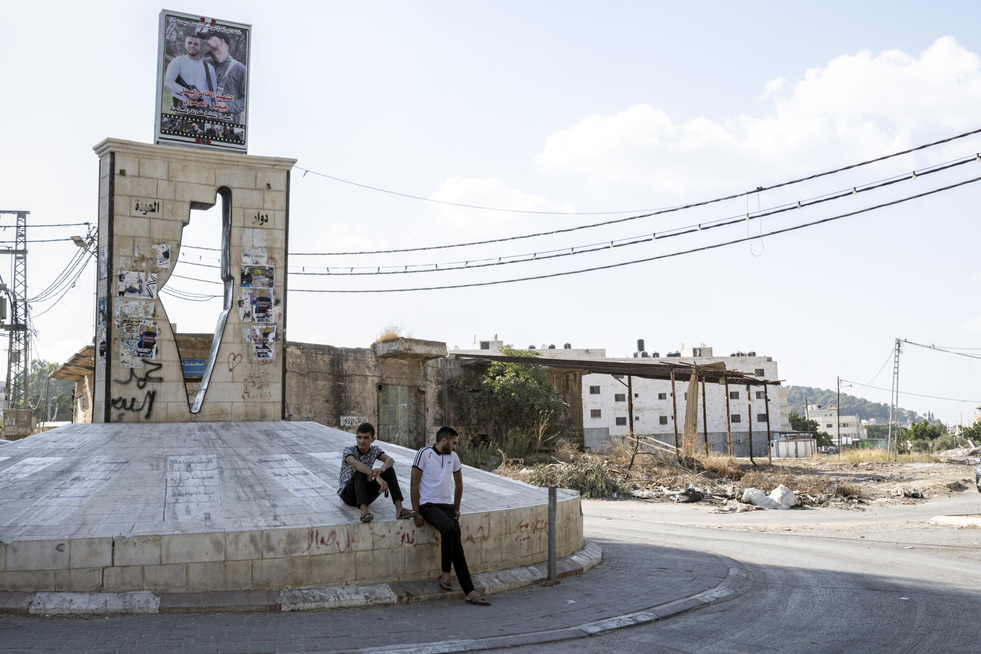 Des jeunes de Jénine (Cisjordanie) sont assis sur un rond-point au sommet duquel apparaît une photo d’un « martyr », le 7 septembre 2021.