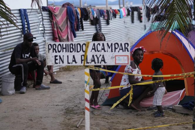 Des migrants haïtiens campent sur la plage de Necocli, en Colombie, lundi 13 septembre 2021. Ils font route vers le nord, vers la frontière américaine. Un panneau indique en espagol « interdiction de camper sur la plage ».