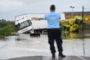 TOPSHOT - A French Gendarme officer looks at two trucks blocked in a flooded road in Codognan, in the Gard department, in the Occitanie region, southern France, on September 14, 2021 following heavy rains. The Gard went into a state of red vigilance on September 14, 2021 at midday due to the risk of flooding following thunderstorms and heavy rains, reported Meteo France, the official meteorology and climatology office in France . (Photo by Sylvain THOMAS / AFP) 