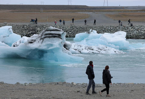 HOF, ICELAND - AUGUST 15: Tourists look at icebergs that have broken off of receding Breidamerkurjokull glacier and are clogging a river leading from Jokulsarlon lake to the ocean on August 15, 2021 near Hof, Iceland. Breidamerkurjokull, among the biggest of the dozens of glaciers that descend from Vatnajokull ice cap, is melting, losing an average of 100 to 300 meters in length annually. Breidamerkurjokull's meltwater has created Jokulsarlon, which is now Iceland's biggest lake. Iceland is undergoing a strong impact from global warming. Since the 1990s, 90 percent of Iceland's glaciers have been retreating and projections for the future show a continued and strong reduction in size of its five ice caps. (Photo by Sean Gallup/Getty Images) (Photo by SEAN GALLUP / GETTY IMAGES EUROPE / Getty Images via AFP)