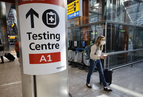 A traveller walks past a sign directing the public to a Covid testing centre at Terminal 5 in west London on August 2, 2021 as quarantine restrictions ease. - People fully vaccinated in the United States and European Union, except France will now be allowed to travel to England without having to quarantine on arrival. (Photo by Tolga Akmen / AFP)