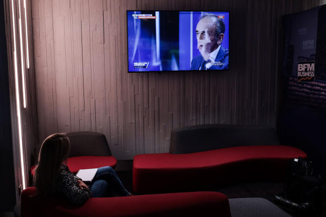 Une femme regardant le débat entre Eric Zemmour et Jean-Luc Mélenchon sur BFM-TV, dans les couloirs de la chaîne, à Paris, le 23 septembre 2021.