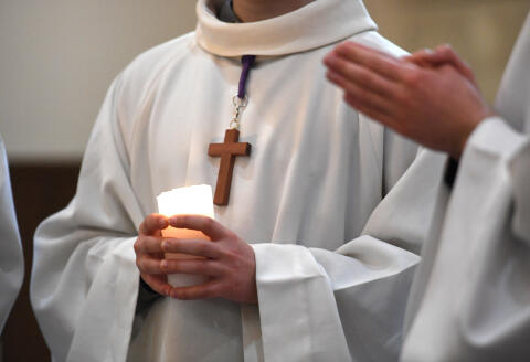 An altar boy holds a candle during a mass in Brest, western France, on March 27, 2021. (Photo by Fred TANNEAU / AFP)