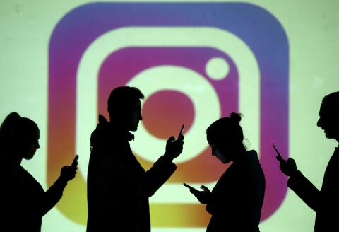 FILE PHOTO: Silhouettes of mobile users are seen next to a screen projection of Instagram logo in this picture illustration taken March 28, 2018. REUTERS/Dado Ruvic/Illustration/File Photo