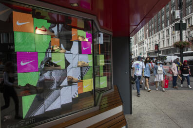 People walk past a Nike store in Midtown New York on August 9, 2021. - Stock markets were mostly lower on Monday, weighed down by a slump in oil prices over concerns about the economic impact of rising infections from Covid's highly contagious Delta variant. (Photo by Kena Betancur / AFP)