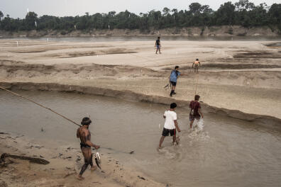 VALE DO JAVARI, BRAZIL - AUGUST 12, 2021: A group of Kanamari men walk along the Javari River returning from a patrol inside their territory. In recent years, their land has been increasily targeted by illigal fishermen, hunters and loggers who put at risk their livelihood. In the absence of resources and an efficient protection policy by the National Indigenous Foundation (FUNAI), the Kanamari have organized themselves and are trying to create managment areas to preserve wildlife and encourage sustainable fishing.