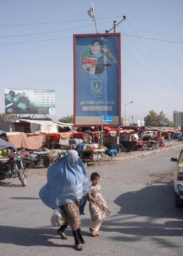 Une femme et sa fille passent devant une publicité pour une école avec le slogan  « Chercher la lumière », au centre de Mazar-e Charif, le 10 septembre 2021.