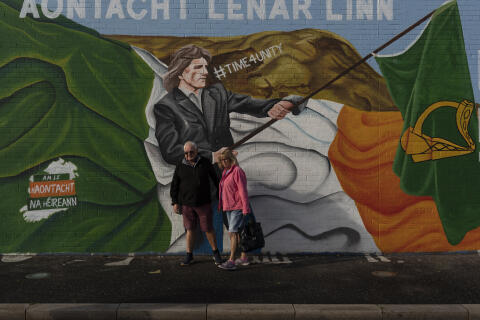 Tourists posed beside Republican murals calling for the reunification of Ireland, along the Falls Road, a prominent Nationalist Catholic area in West Belfast, Northern Ireland, on September 29, 2021.