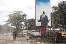 Two women walk past a defaced billboard of former President of Guinea, Alpha Conde, in Conakry on September 16, 2021. Colonel Mamady Doumbouya’s special forces on September 5, 2021 seized Alpha Conde in a Coup, the West African state's 83-year-old president, a former champion of democracy accused of taking the path of authoritarianism. (Photo by JOHN WESSELS / AFP)