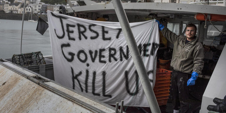 GRANVILLE, FRANCE - MAY 06: French fishermen who have just returned from sea protesting with a fleet of fishing boats in the territorial waters of Jersey show a banner that reads 