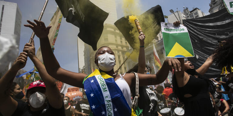 A woman, wrapped in a Brazilian national flag, chats slogans during a protest against Brazilian President Jair Bolsonaro calling for his impeachment over his government’s handling of the pandemic and accusations of corruption in the purchases of COVID-19 vaccines, in Rio de Janeiro, Brazil, Saturday, Oct. 2, 2021. (AP Photo/Bruna Prado)