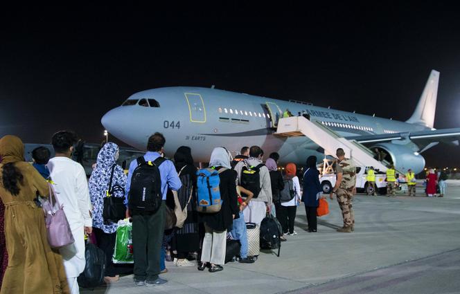 Des réfugiés afghans embarquent à bord d’un Airbus de l’Armée de l’air française lors d’une escale aux Emirats arabes unis, le 23 août.