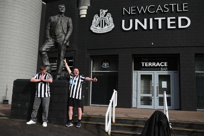 Des supporteurs de Newcastle United posent avec la statue de l’ancien manageur Bobby Robson devant le stade du club, à St James’ Park, à Newcastle-upon-Tyne, dans le nord-est de l’Angleterre, le 8 octobre 2021.