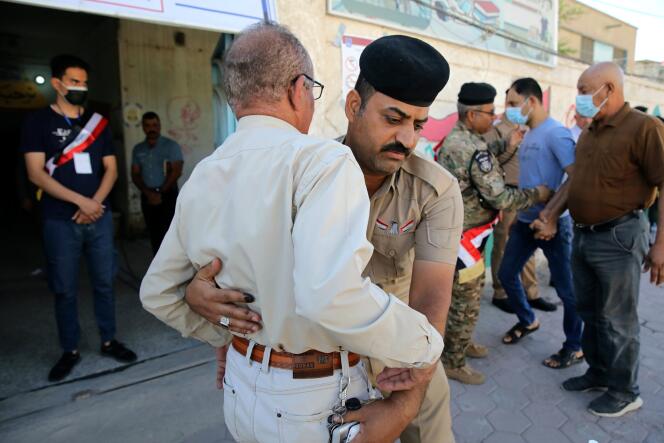 Security forces search people outside a polling station during parliamentary elections in Basra, Iraq on October 10, 2021.
