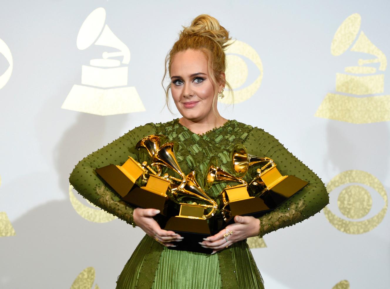 Adele holds the awards she received for her album