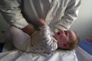 Un kinésithérapeute effectue, le 03 novembre 2003, un massage respiratoire sur un bébé de 9 mois atteint par la bronchiolite, une maladie des bronches due à un virus et qui touche chaque hiver près de 30 % des nourrissons. Le gouvernement a lancé une campagne de prévention pour alerter les parents sur des gestes simples permettant d'enrayer l'épidémie. (Photo by MYCHELE DANIAU / AFP)