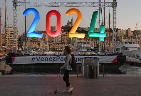 A woman on a scooter rides past an inflatable '2024' logo in the old harbour area of Marseille late September 13, 2017, during celebrations after the International Olympic Committee (IOC) official announcement that Paris won the 2024 Olympic bid. - French President Emmanuel Macron has hailed the decision to award the 2024 Olympics to Paris as a "victory for France". Macron said after the International Olympic Committee vote in Lima that rubber-stamped the historic double award of the 2024 Games to Paris and the 2028 Olympics to Los Angeles that "the whole country must get behind" the event. (Photo by BORIS HORVAT / AFP)