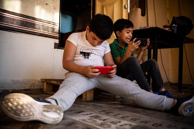 Yelissey et Flavius jouent sur des smartphones, au camp de la Flambère, à Toulouse, le 30 septembre 2021.
