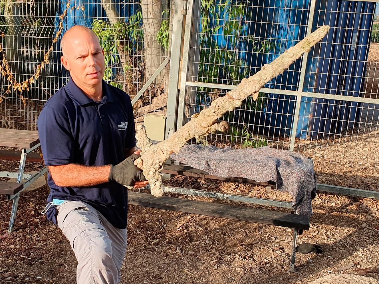 Il ricercatore dell'AIA Nir Distelfeld tiene in mano la spada scoperta.